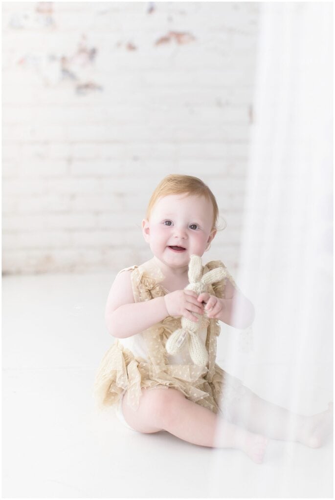 Adorable baby girl holding a knit bunny toy, high-quality portrait, natural lighting, professional children’s photography, Mary Christine Photography.