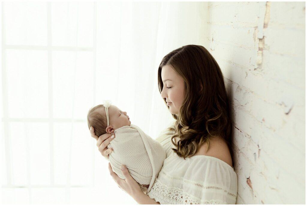 Professional working mother holding newborn baby during boutique photography session at Akron studio