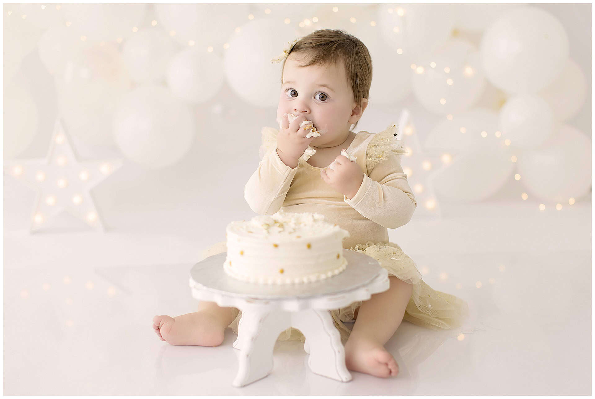 Close-up of baby’s happy expression with frosting on her face during cake smash.
