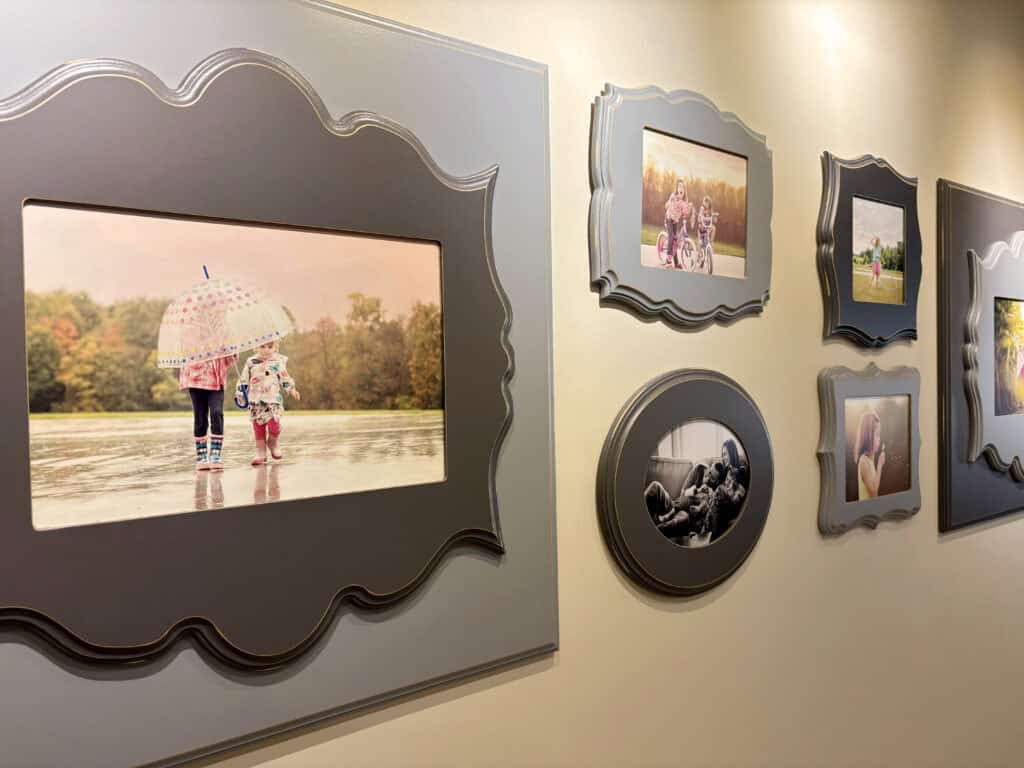 Framed family photos displayed in a home hallway, showing children playing outdoors—a reminder of why family photos are important.
