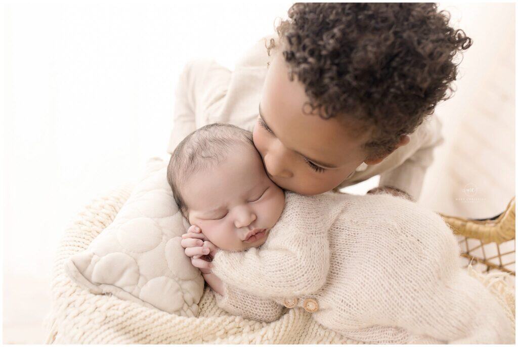 Toddler sibling warming up during a relaxed newborn photo session in a studio setting
