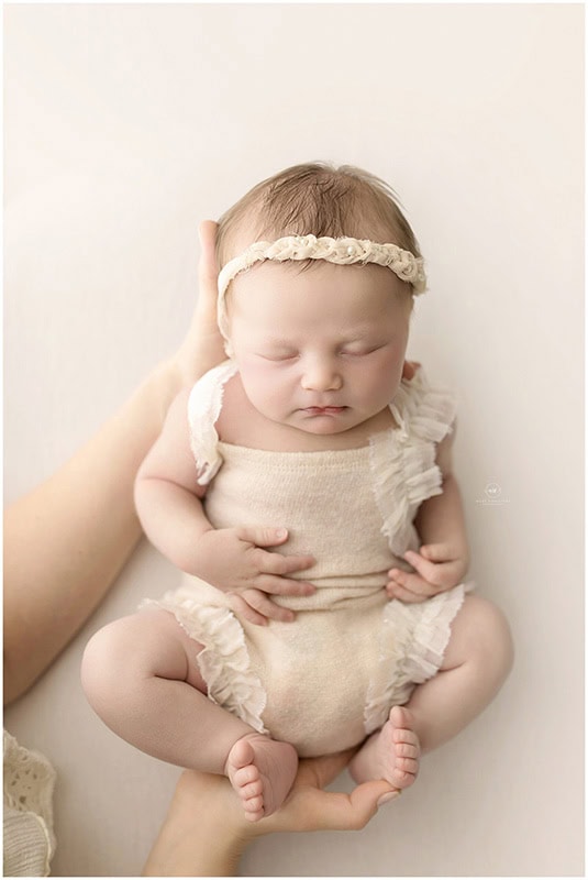 Parent holding newborn during a relaxed newborn photo session with essential items nearby