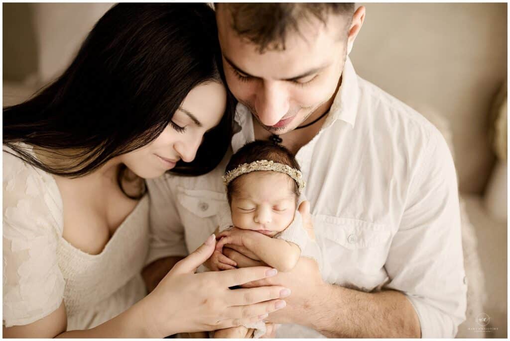 Lifestyle newborn photography in a light and airy studio in Cleveland Ohio with parents holding their sleeping baby