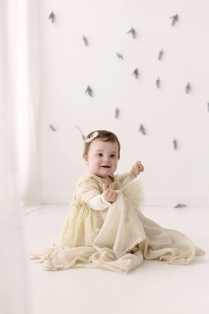 Baby girl smiling during a light and airy milestone photo session with soft neutral styling