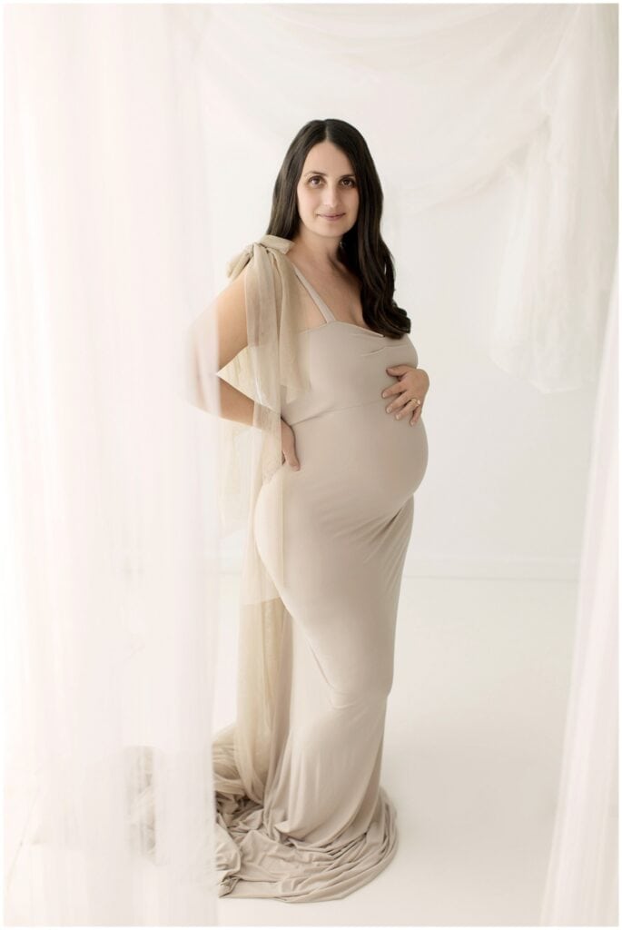 Pregnant mom in a lace gown during a Cleveland studio maternity session with soft natural hair and makeup