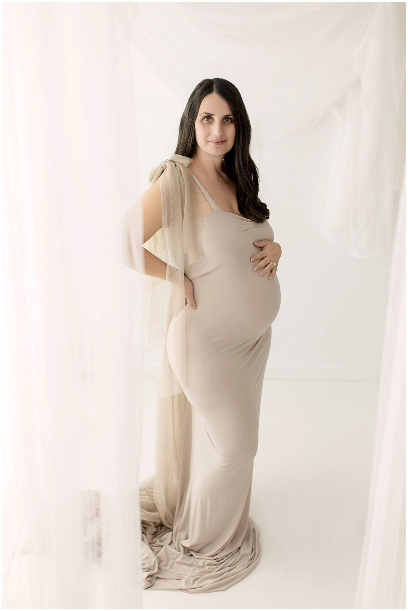 Pregnant mom in a lace gown during a Cleveland studio maternity session with soft natural hair and makeup